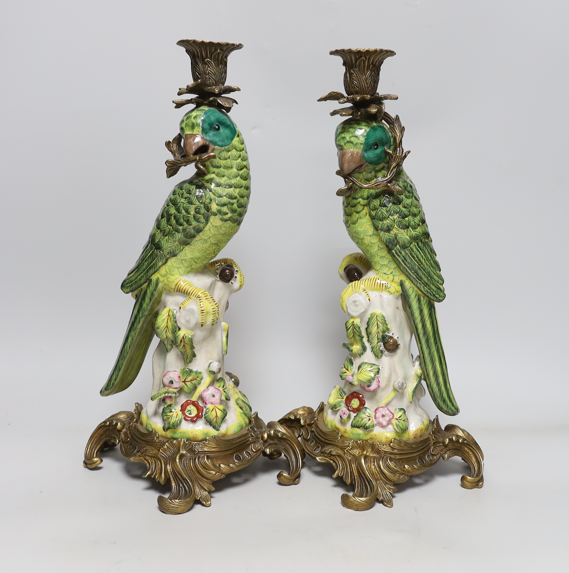 A pair of modern gilt metal mounted ceramic parrot candlesticks, 36cm